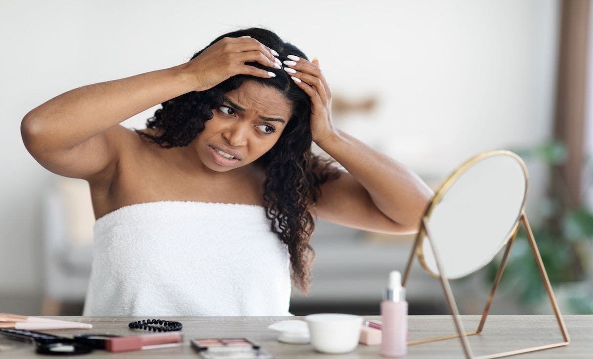 Black woman with hair concern | Image Credit: Prostock-studio-stock.adobe.com