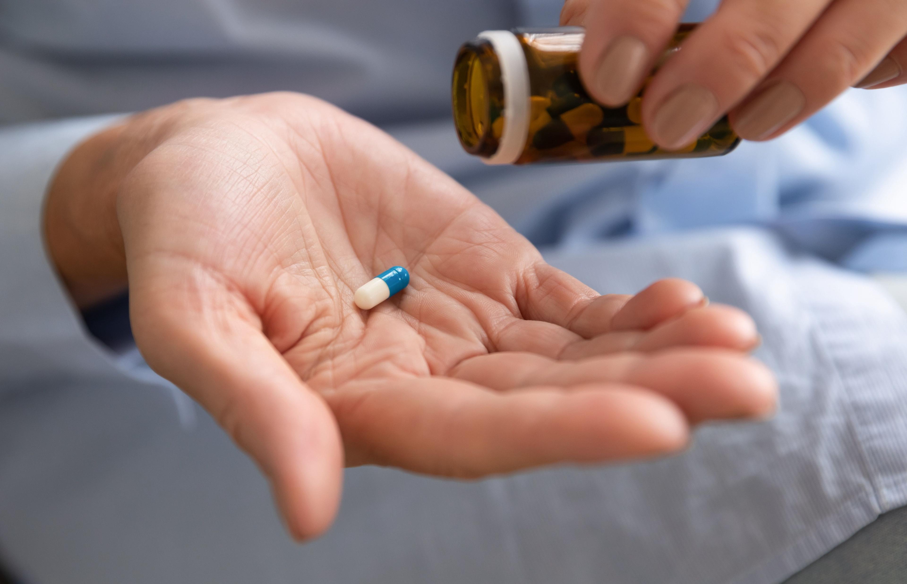 Older woman taking out dose of pills from glass bottle - fizkes - stock.adobe.com