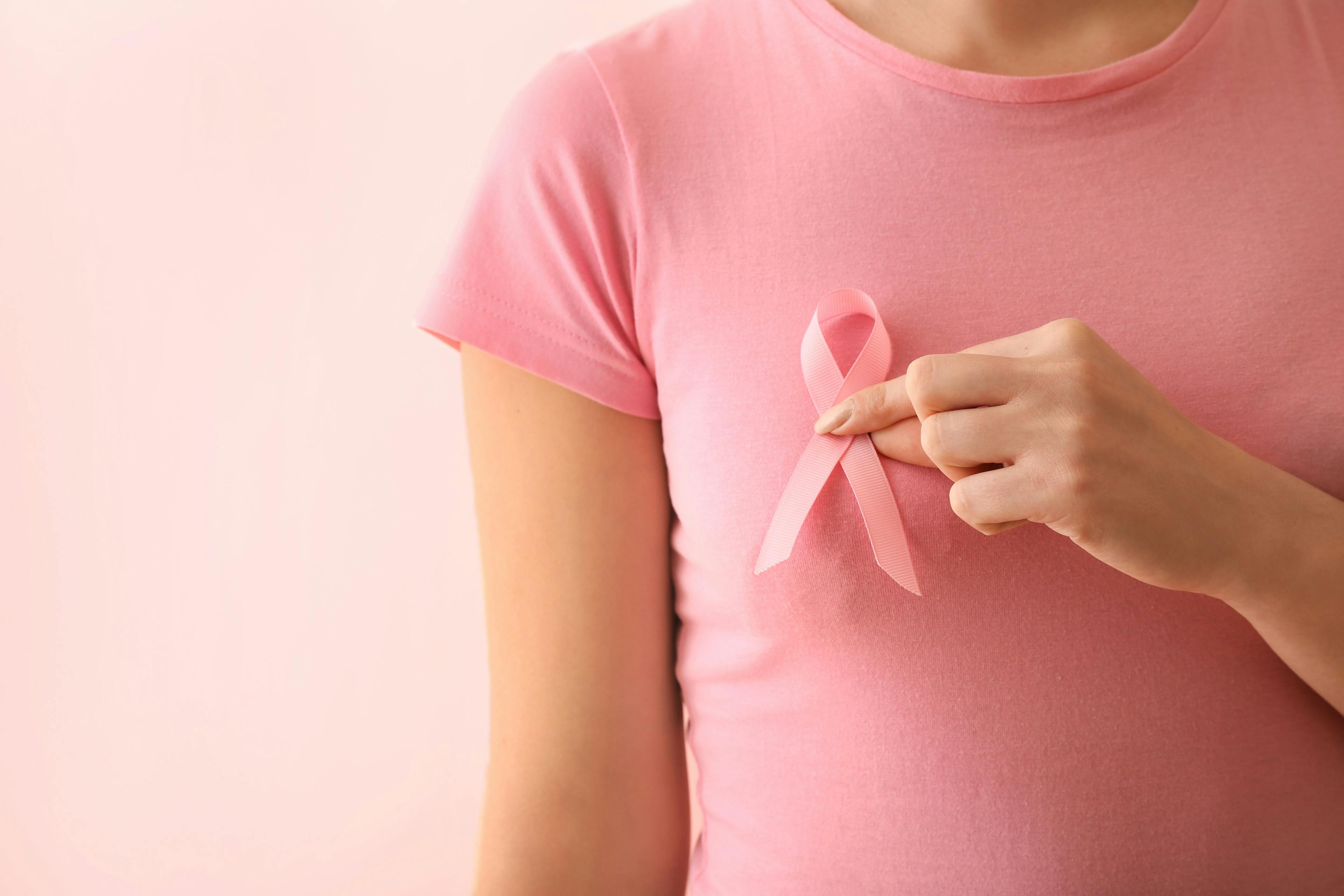 Female patient holding up breast cancer awareness ribbon | Image Credit: Pixel-Shot - stock.adobe.com