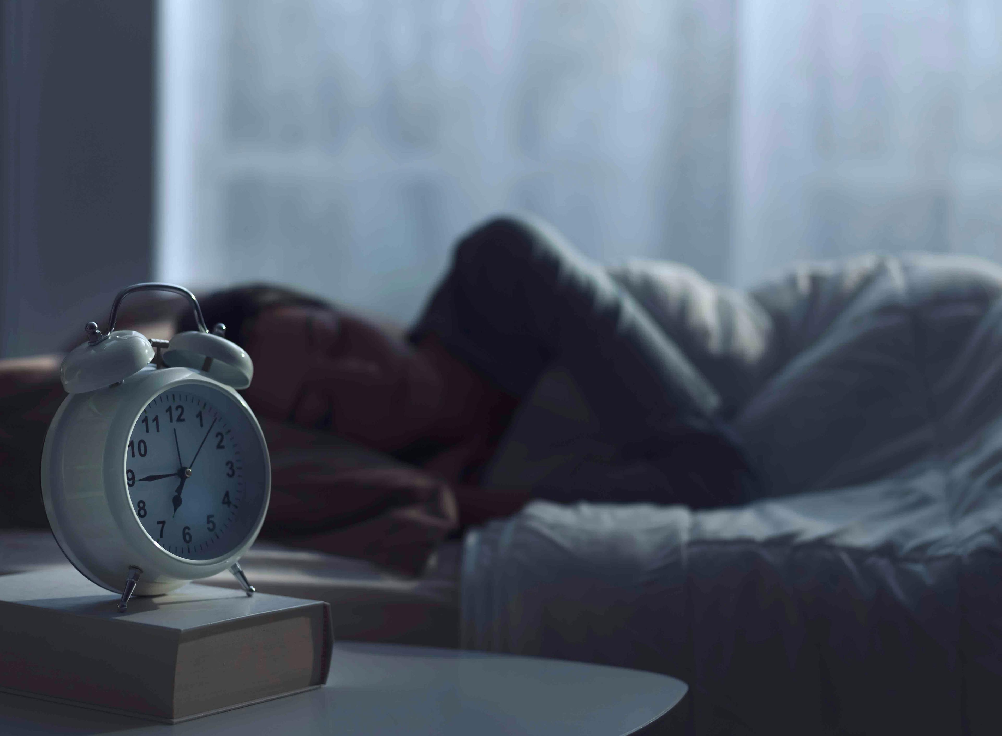 Woman sleeping next to alarm clock | Image Credit: stokkete - stock.adobe.com.jpg