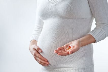 Pregnant person holding pills