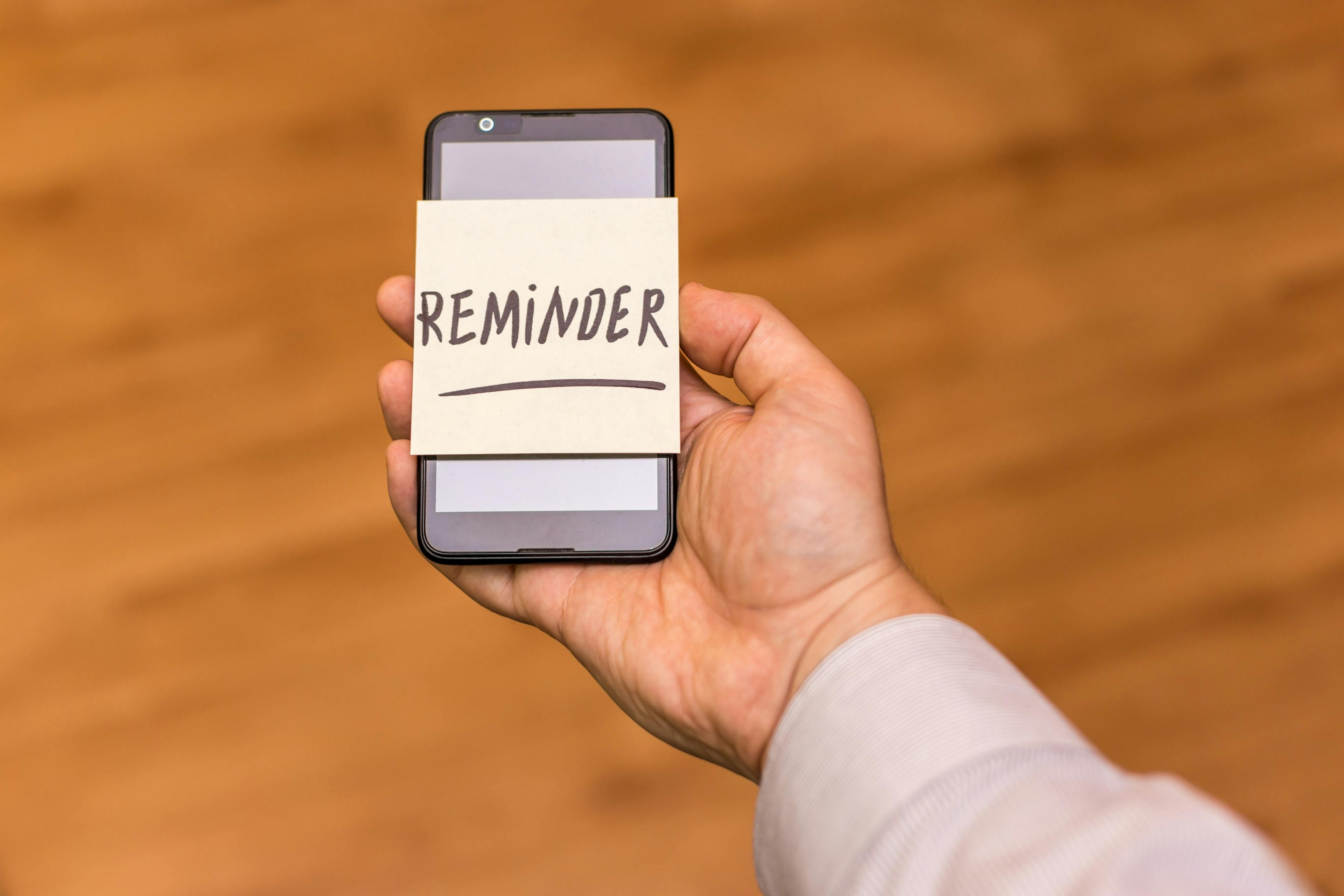 person holding phone with note reading "reminder"