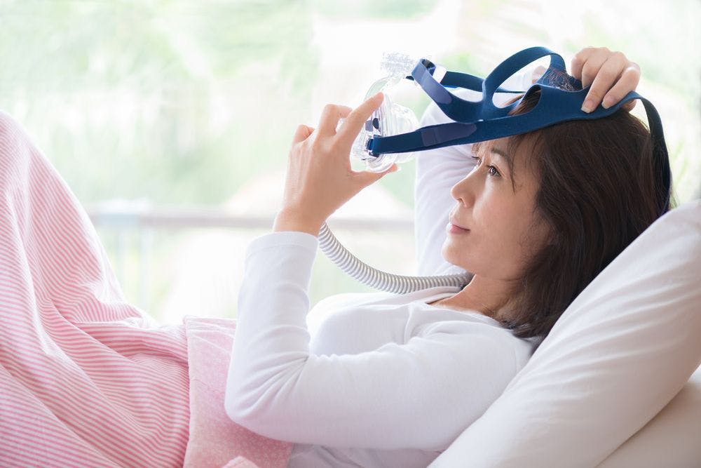 Woman putting on a CPAP machine.