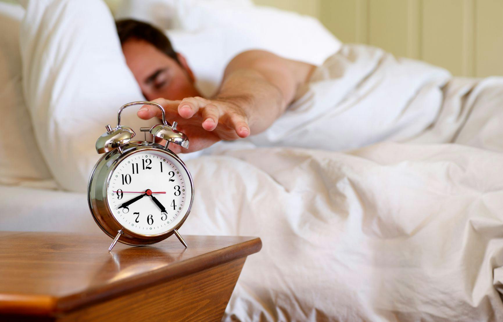Person hitting snooze alarm when awakening.