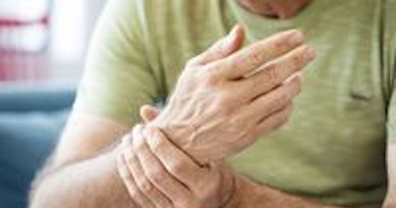 Older man with Parkinson disease gripping hand.