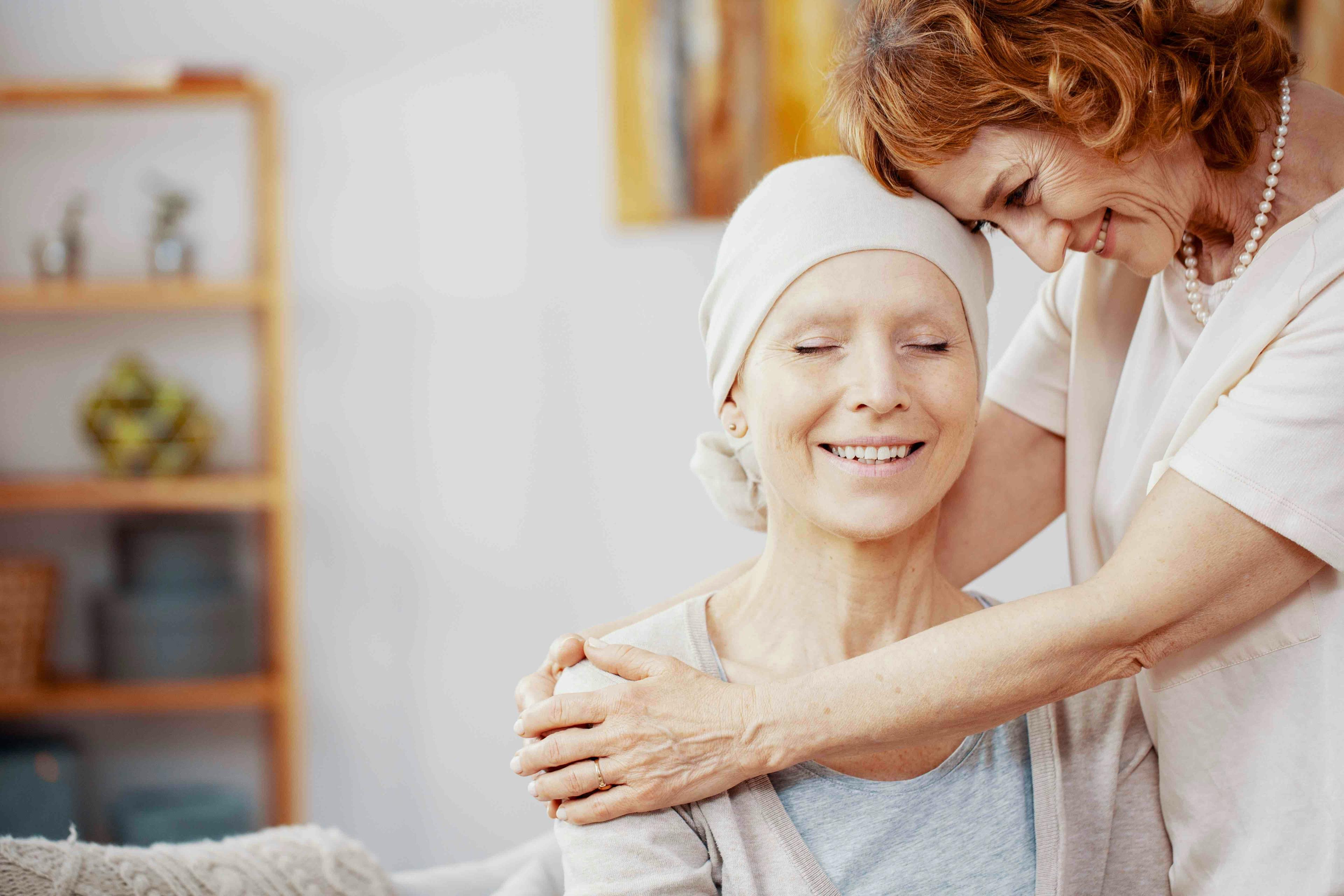 senior redhead women kissing forehead of her happy best friend with cancer Stock Photo | Image Credit: Adobe Stock
