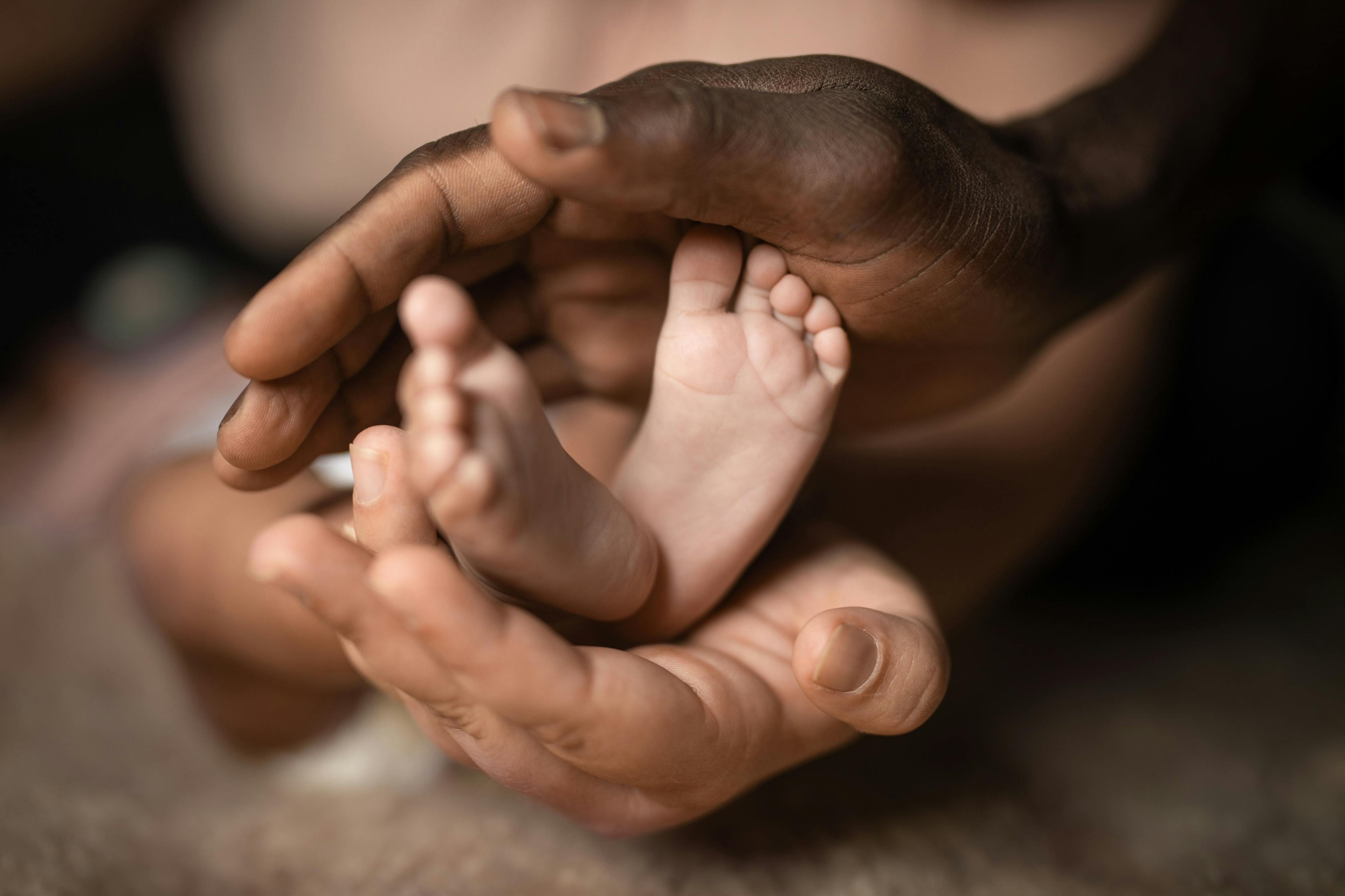 Interracial family holding baby feet in hands mixed by black and white skin color | Image credit: Shotmedia - stock.adobe.com